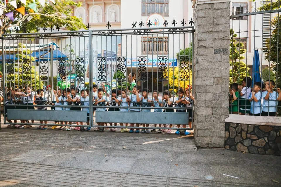 Children Peering Through School Gate Outdoors