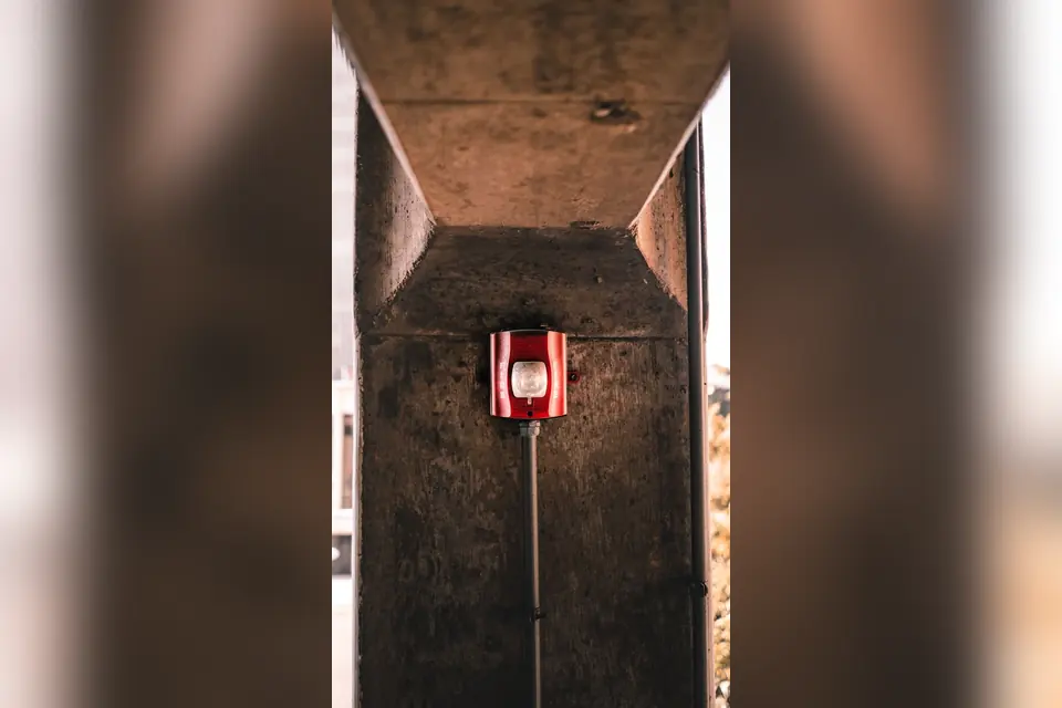 Red fire alarm box on stone building